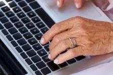 Hände einer älteren Frau auf einem Computer