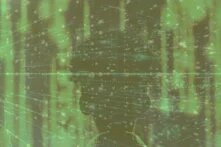 Silhouette eines menschlichen Kopfes, überlagert von grün leuchtenden Datenströmen und digitalen Netzstrukturen, die an Matrix-Code erinnern