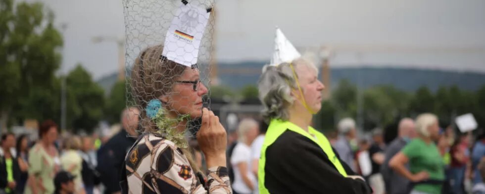 Participants take part in a demonstration against Coronavirus restrictions in Stuttgart, Germany on May 9, 2020. Similar protests and actions are being held worldwide with people asking for freedom of movement and religious ceremonies. One Person is wearing an aluminium hat, another is wearing a metal net around her head with the constiution on it.